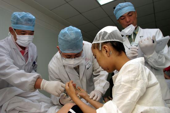 图文:医生检查伤员手的受伤情况