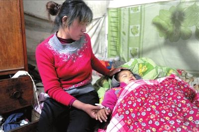 孩子躺在床上，母亲坐在床头抚摸孩子的伤口。本报记者潘之望摄