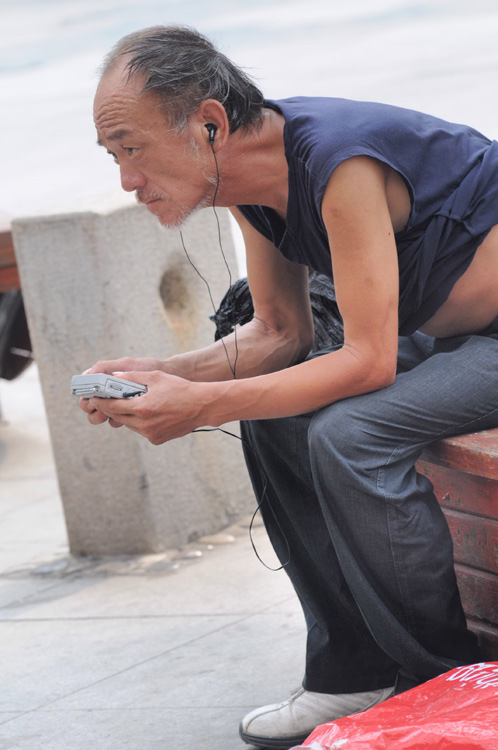 图文老汉坐在休闲椅上收听奥运赛况