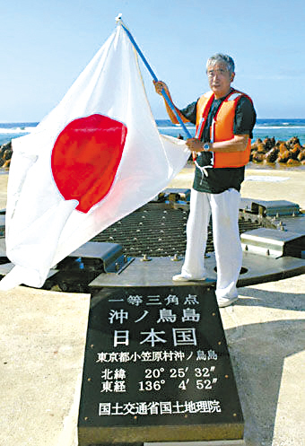 2005年,日本东京都知事石原慎太郎登上冲之鸟礁挥舞日本国旗