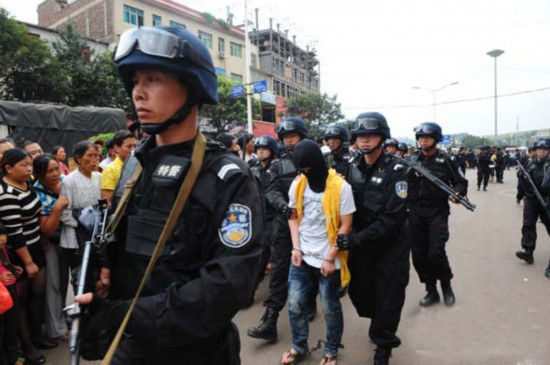 去年9月,警察押解两人在云南富源县犯罪现场进行指认,图中戴头套者为