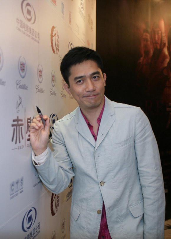 梁朝伟在凯迪拉克logo墙前签名