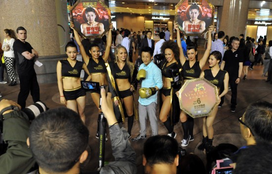 3月27日,两届奥运拳击冠军邹市明(中)与举牌女郎合影.