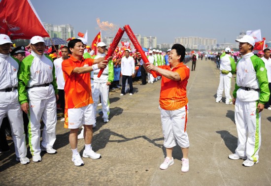 11月2日,第80棒火炬手莫章德(左)与第79棒火炬手江春燕进行圣火交接